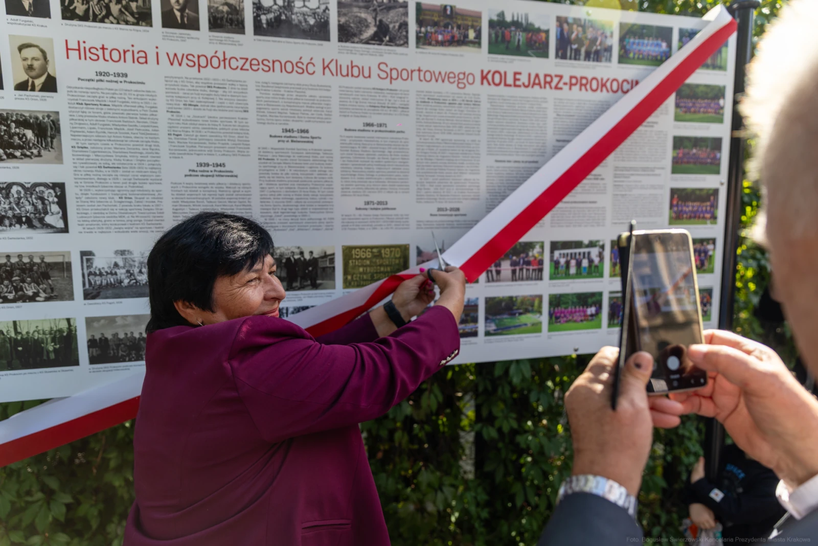 Kobieta przecina wstęgę przy tablicy upamiętniającej historię Klubu Sportowego Kolejarz-Prokocim.  Autor: Bogusław Świerzowski