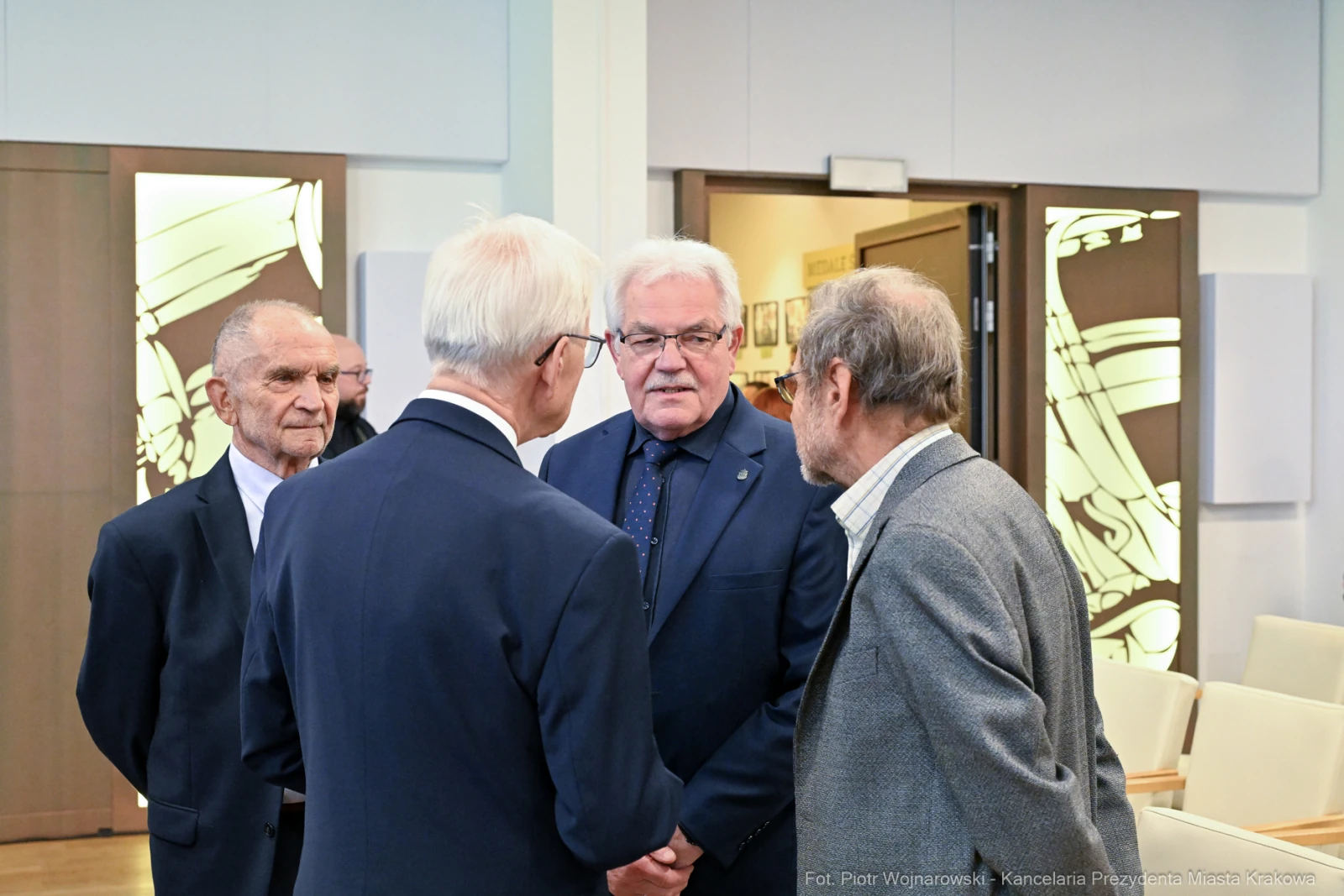 Spotkanie czterech mężczyzn w formalnych strojach, rozmawiających w eleganckim wnętrzu.  Autor: Piotr Wojnarowski