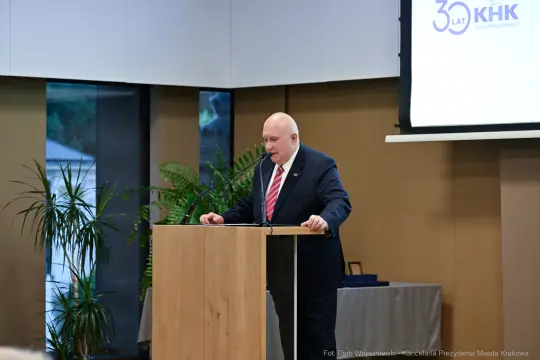 Mężczyzna w garniturze przemawia przy mównicy podczas uroczystości z okazji 30-lecia KHK.