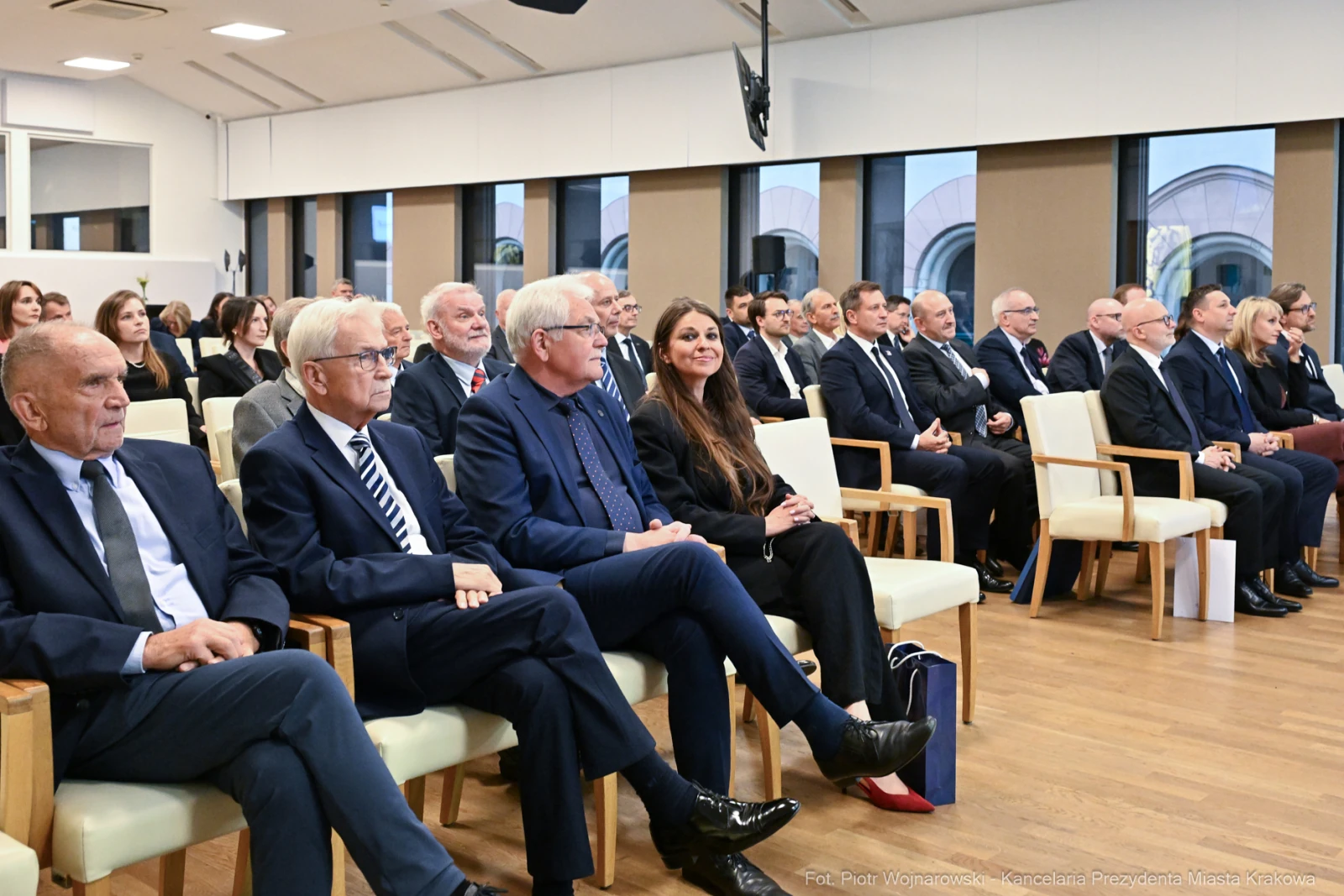Grupa ludzi siedzących w sali konferencyjnej, ubranych w eleganckie stroje.  Autor: Piotr Wojnarowski