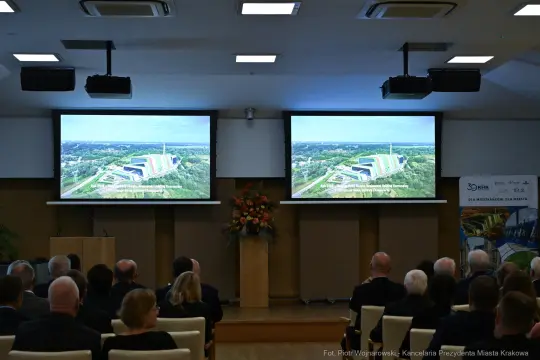 Prezentacja multimedialna w sali konferencyjnej z widokiem na miasto.