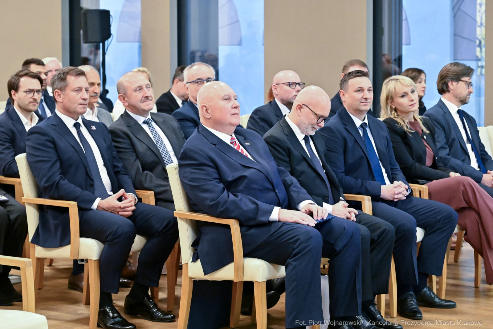 Grupa mężczyzn i kobiet w formalnych strojach siedzących w sali podczas wydarzenia.  Autor: Piotr Wojnarowski