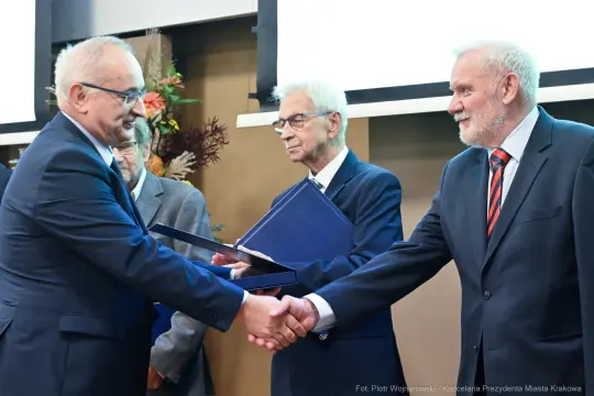 Wręczenie nagrody, uściski dłoni, mężczyźni w garniturach, ceremonia.