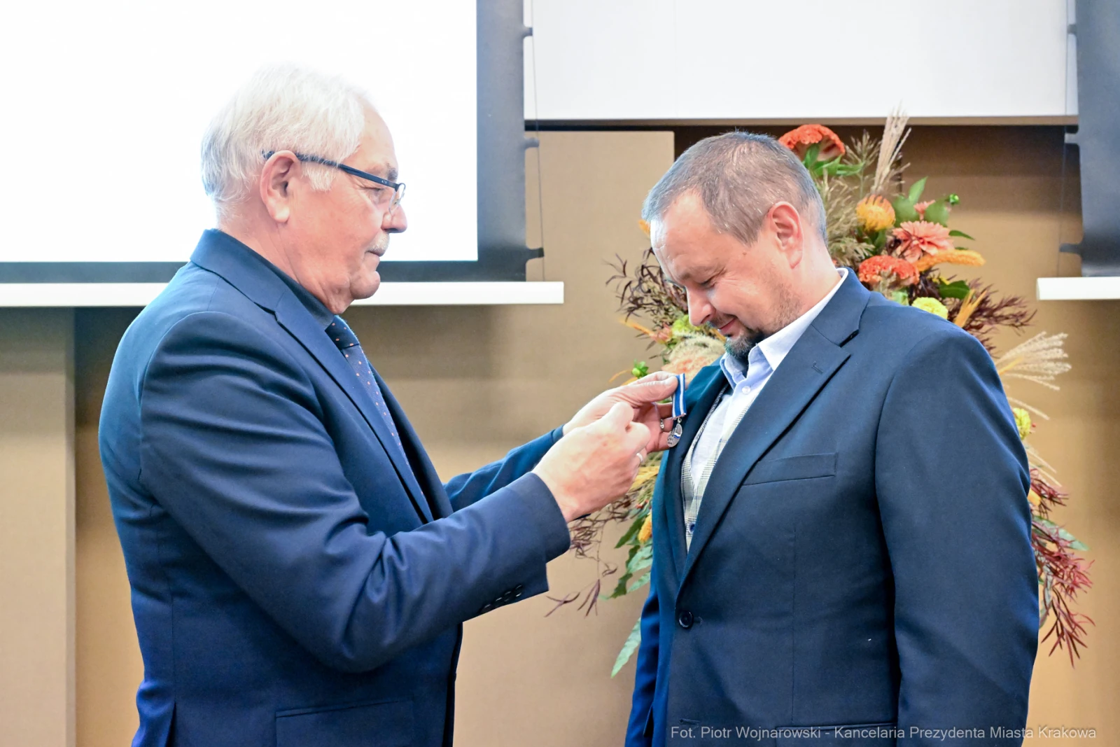 Mężczyzna odbiera medal od innego mężczyzny podczas uroczystości.  Autor: Piotr Wojnarowski