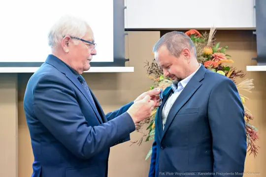 Mężczyzna odbiera medal od innego mężczyzny podczas uroczystości.