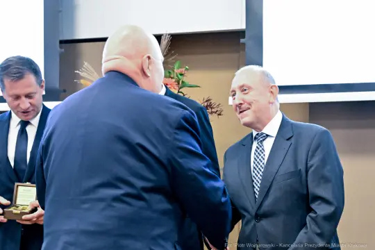 Wręczenie nagrody podczas uroczystości z udziałem kilku mężczyzn.