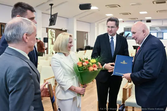 Uroczystość wręczenia nagrody z bukietem kwiatów i gratulacjami.