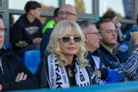 Kobieta w okularach przeciwsłonecznych z szalikiem drużyny sportowej.