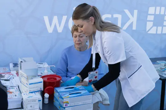Kobieta w białym fartuchu medycznym przygotowuje materiały w punkcie zdrowotnym.