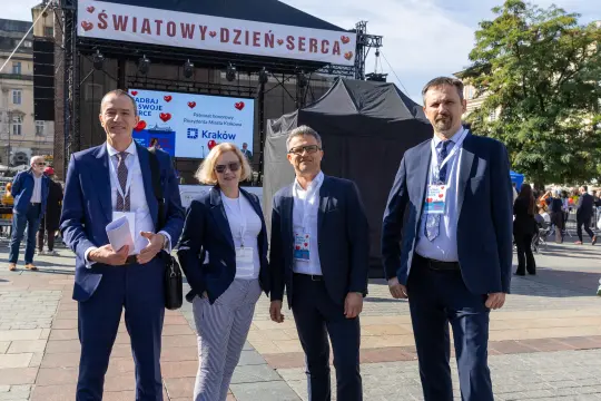 Cztery osoby w garniturach na tle sceny z wydarzenia Światowy Dzień Serca.