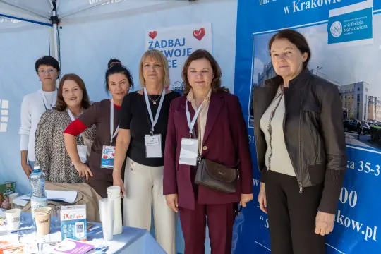 Grupa kobiet przy stoisku informacyjnym na wydarzeniu.
