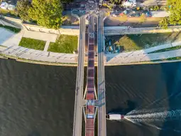 Most nad rzeką z widokiem na wodę i otaczającą zieleń.