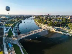 Most nad rzeką z widokiem na miasto i balon na gorące powietrze w tle.
