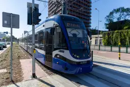 Tramwaj linii 12 na ulicy, w tle nowoczesny budynek.