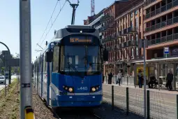 Tramwaj linii 16 na przystanku w mieście, obok budynków mieszkalnych.