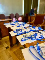 Medale i identyfikatory na stołach w sali konferencyjnej.