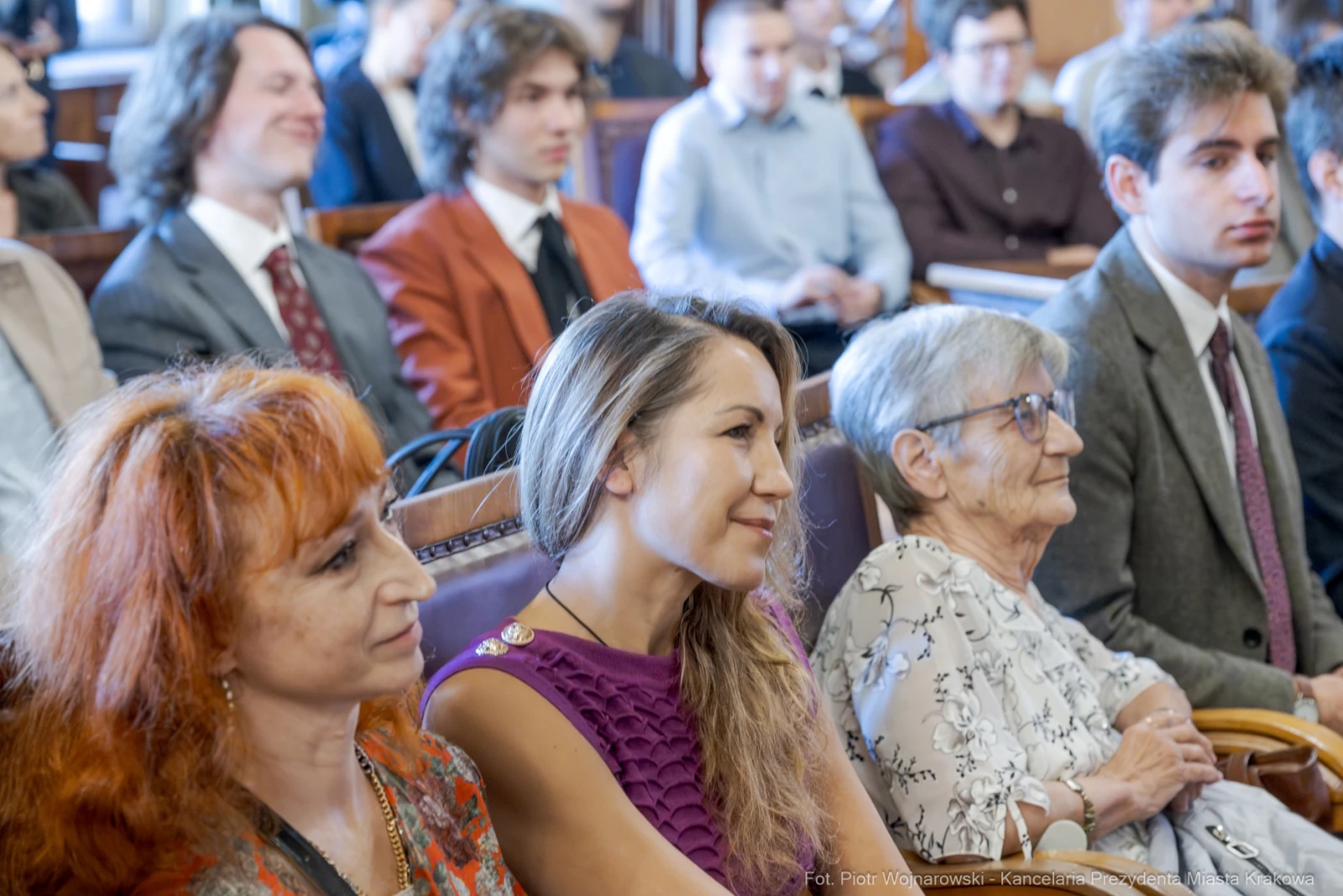 Grupa osób siedzących w sali, uśmiechnięte twarze, różnorodne stroje.  Autor: Piotr Wojnarowski