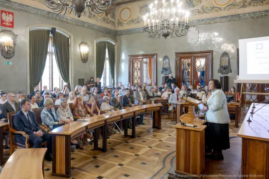 Spotkanie w sali obrad z prelegentką i uczestnikami w tle.