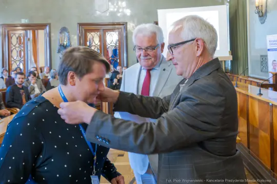 Wręczenie nagrody podczas uroczystości w sali konferencyjnej.