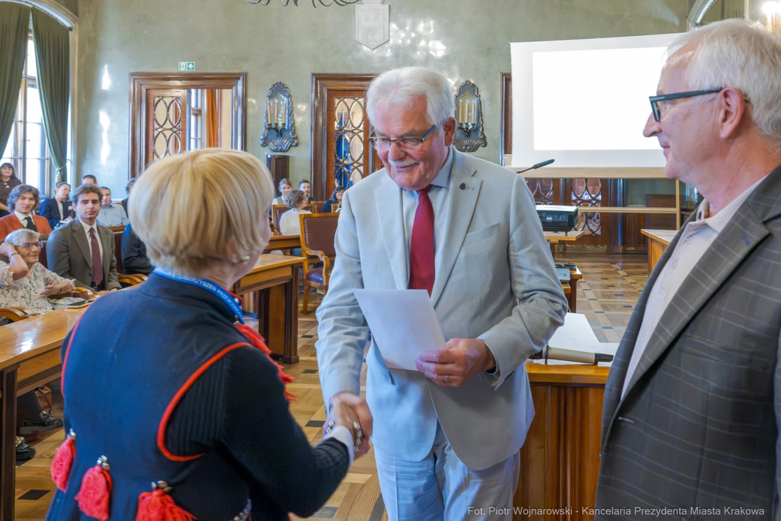 Wręczenie nagrody przez urzędnika miejskiego podczas ceremonii w sali obrad.  Autor: Piotr Wojnarowski
