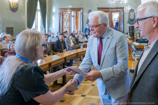 Wręczenie nagrody przez przedstawiciela miasta Krakowa. Uczestnicy w tle.