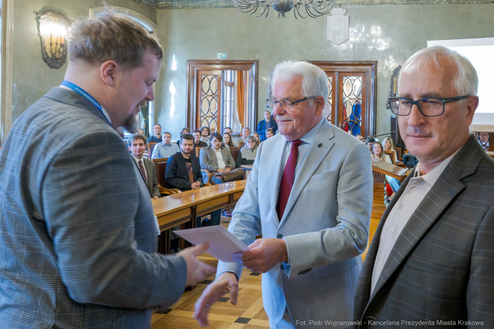 Wręczenie dyplomu w sali obrad z udziałem trzech mężczyzn.  Autor: Piotr Wojnarowski