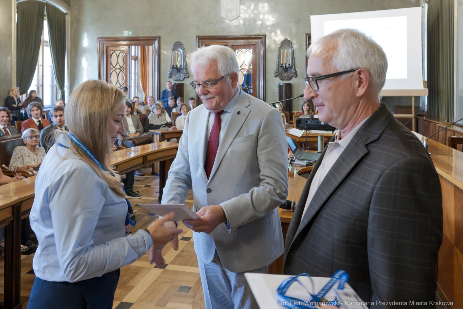 Wręczenie nagród w sali obrad, uczestnicy w formalnych strojach, uśmiechy i gratulacje.  Autor: Piotr Wojnarowski