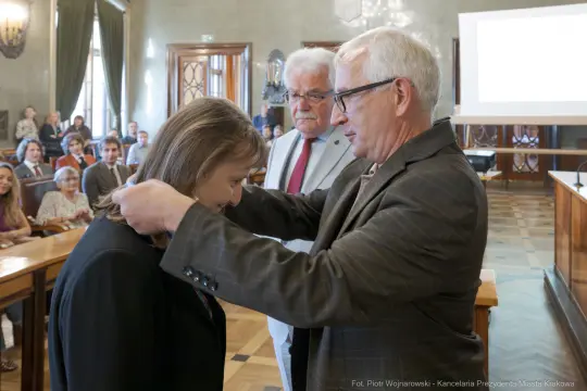 Uroczystość wręczenia odznaczenia w sali obrad z obecnością gości.