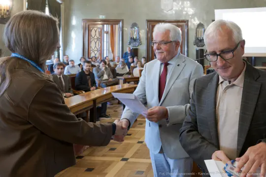 Wręczenie nagród podczas konferencji, uczestnicy w tle.