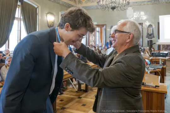 Uroczystość wręczenia medalu młodemu laureatowi w sali obrad.