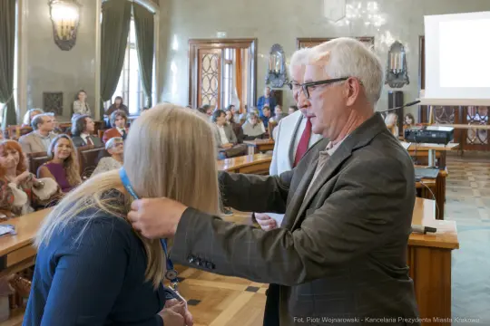 Wręczenie medalu podczas uroczystości w sali obrad.