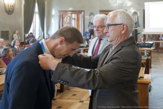 Wręczenie medalu podczas uroczystości w sali obrad.