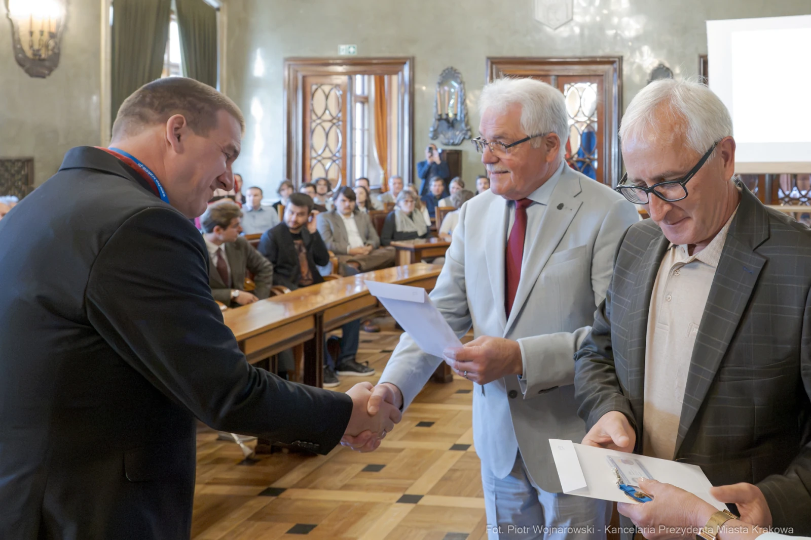 Wręczenie nagród podczas uroczystości w sali obrad z uczestnikami i wręczającymi dokumenty.  Autor: Piotr Wojnarowski