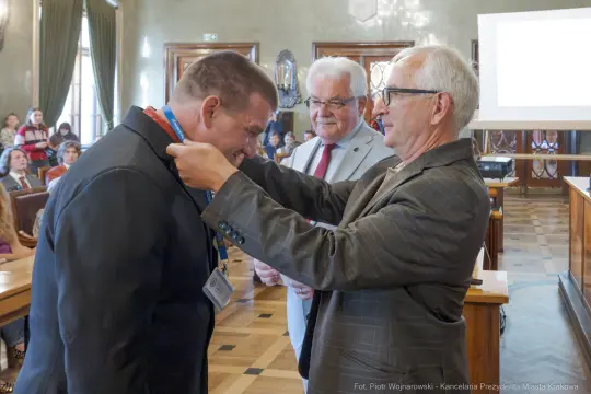 Mężczyzna otrzymuje medal podczas uroczystości w sali obrad.