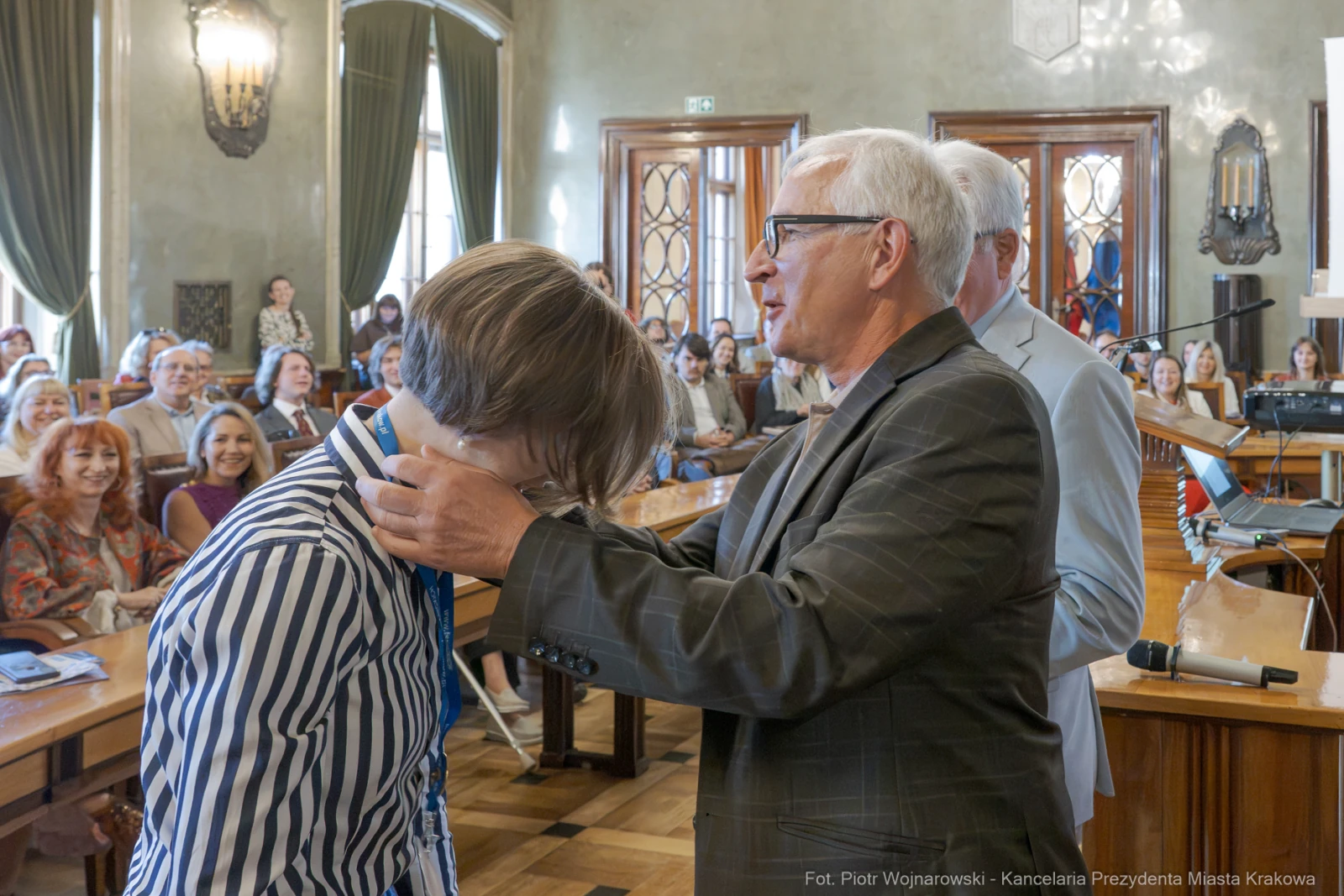 Wręczenie nagrody podczas uroczystości w sali obrad z uśmiechniętymi uczestnikami.  Autor: Piotr Wojnarowski