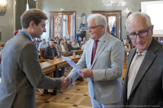 Uroczystość wręczenia nagrody w sali obrad z uśmiechniętymi uczestnikami.