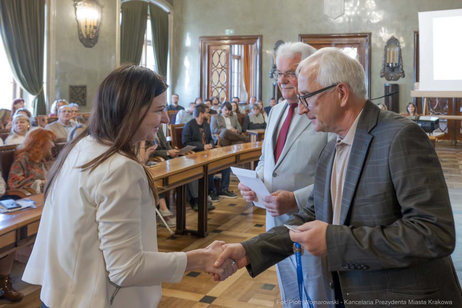 Uroczystość wręczenia nagród w sali obrad z uściskiem dłoni.  Autor: Piotr Wojnarowski
