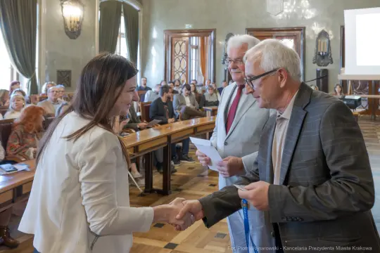 Uroczystość wręczenia nagród w sali obrad z uściskiem dłoni.