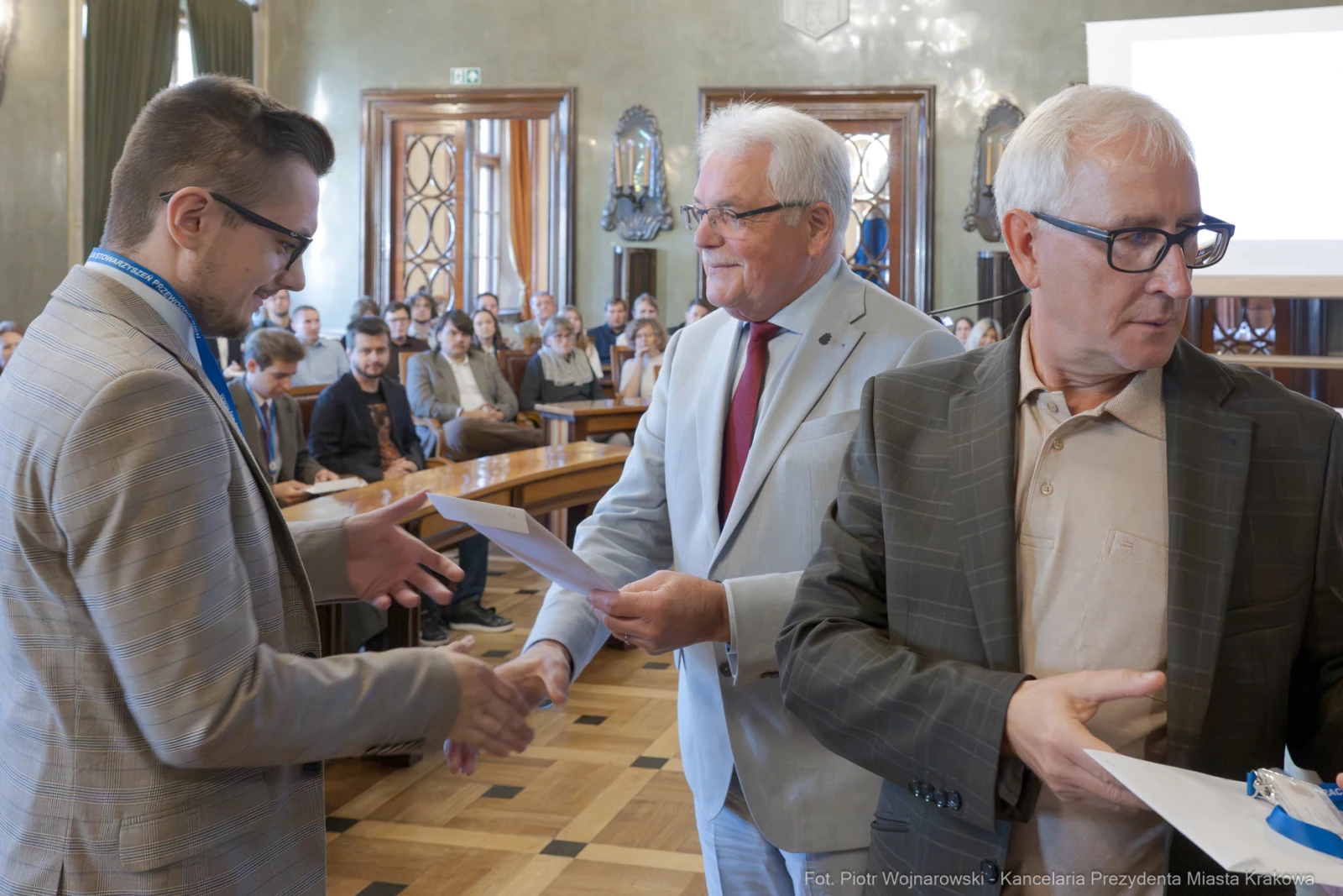 Wręczenie dyplomów w sali obrad, uczestnicy w formalnych strojach.  Autor: Piotr Wojnarowski