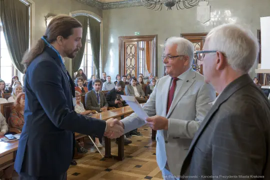 Wręczenie dyplomów w sali konferencyjnej, uściski dłoni i gratulacje.