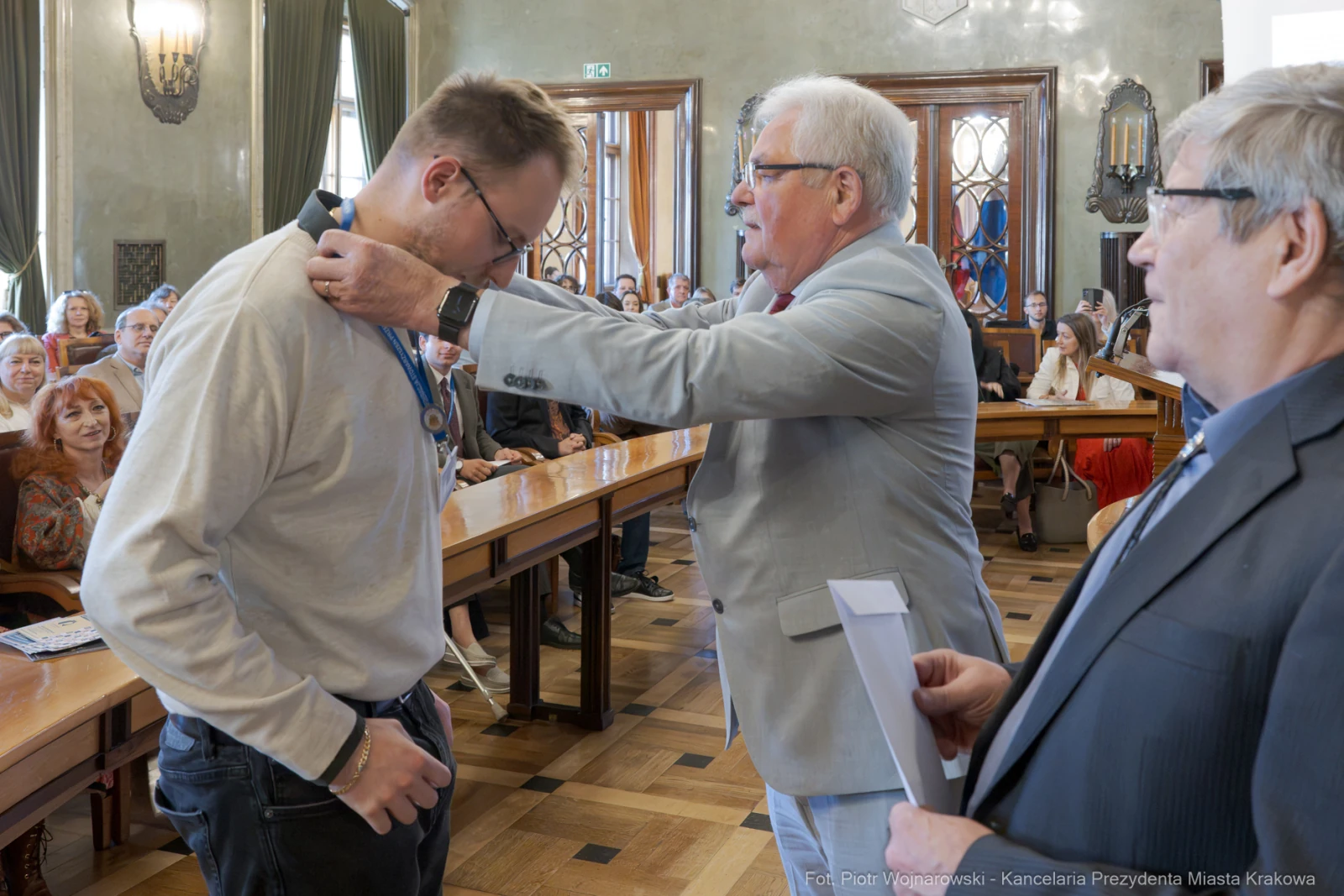 Mężczyzna otrzymuje medal od urzędnika w sali z publicznością.  Autor: Piotr Wojnarowski