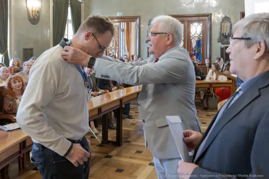 Mężczyzna otrzymuje medal od urzędnika w sali z publicznością.
