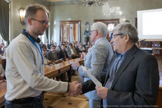 Uroczystość wręczenia nagród w sali miejskiej z uczestnikami i mówcami.