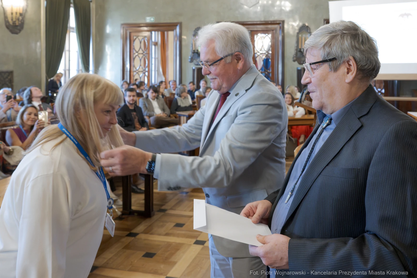 Wręczenie nagrody przez dwóch mężczyzn kobiecie podczas uroczystości w sali.  Autor: Piotr Wojnarowski