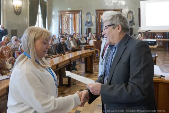 Wręczenie dyplomu podczas uroczystości w sali obrad.