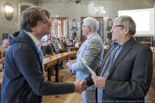 Uroczystość wręczenia nagród, uściski dłoni i gratulacje w sali konferencyjnej.