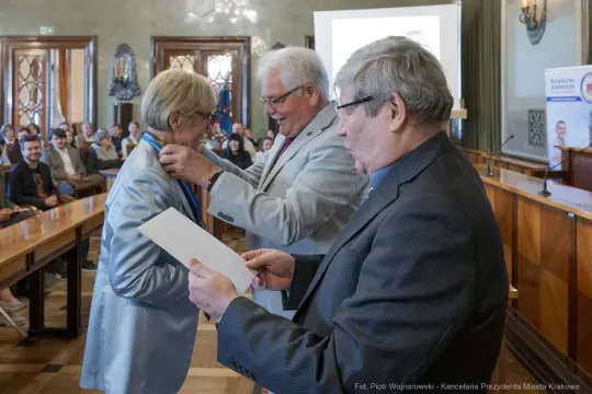 Wręczenie medalu honorowego podczas uroczystości w sali obrad.