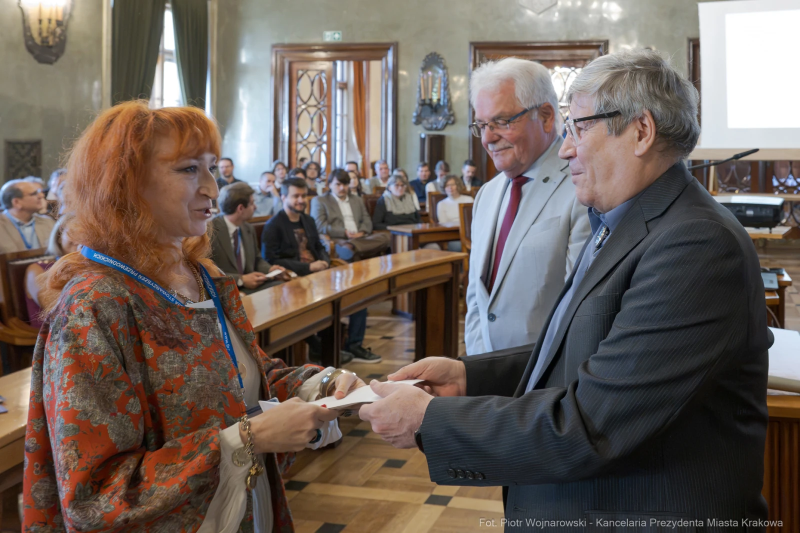 Wręczenie nagrody w sali obrad z uczestnikami w tle.  Autor: Piotr Wojnarowski