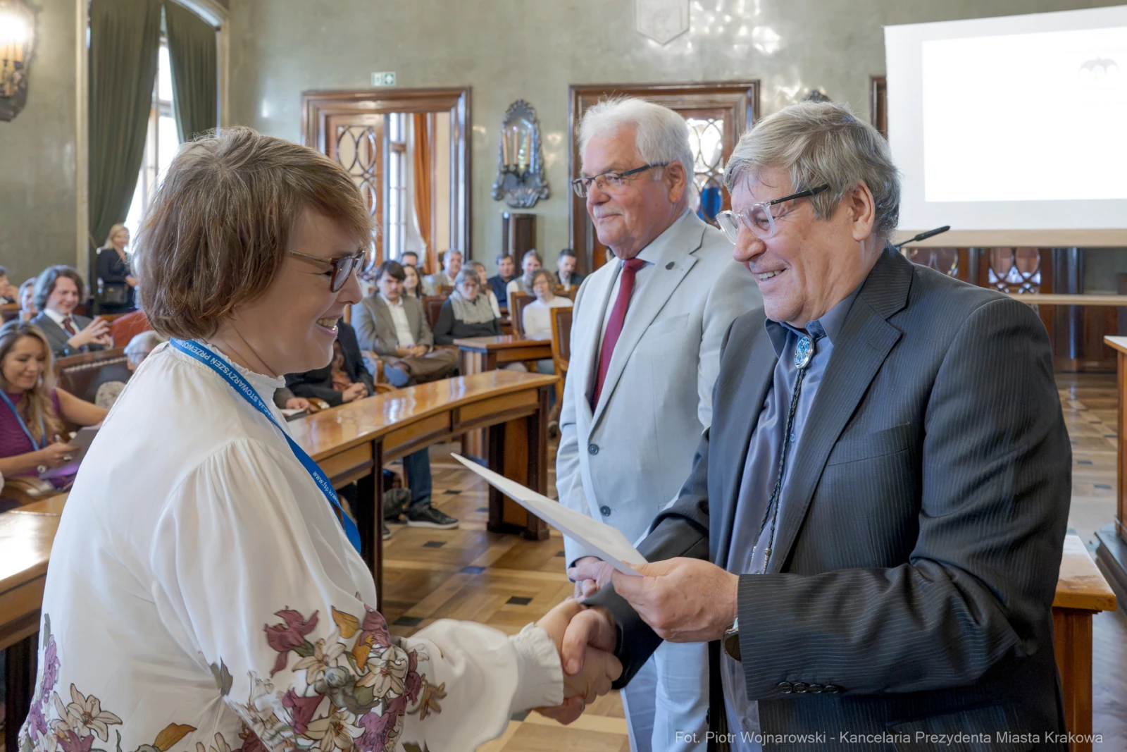Wręczenie nagrody podczas uroczystości w sali obrad z uczestnikami w tle.  Autor: Piotr Wojnarowski