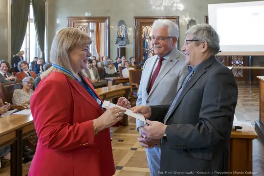 Wręczenie nagrody w sali obrad z uśmiechniętymi uczestnikami.